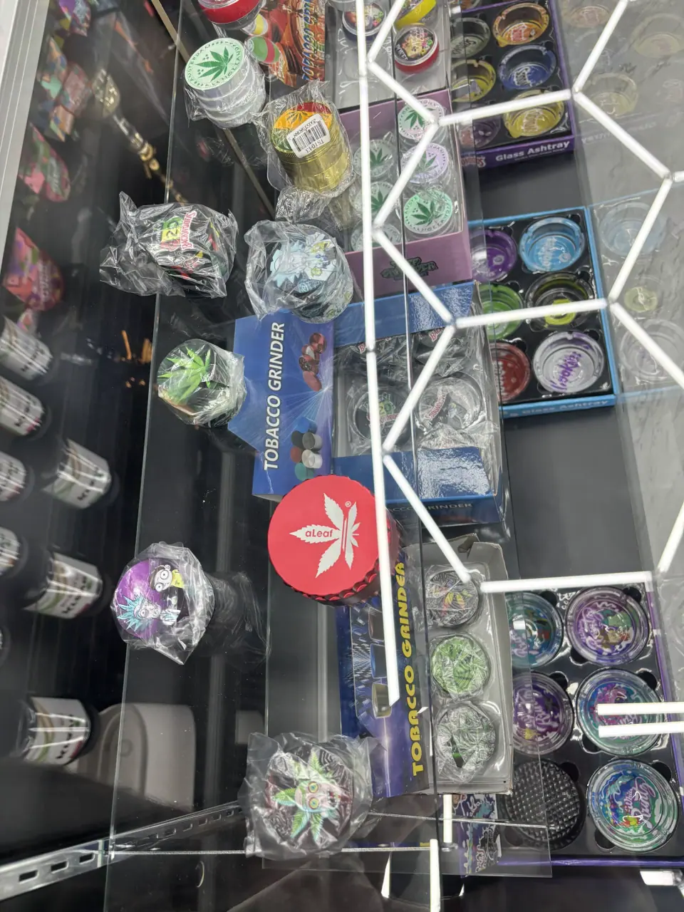 Assorted tobacco grinders displayed inside a glass store counter