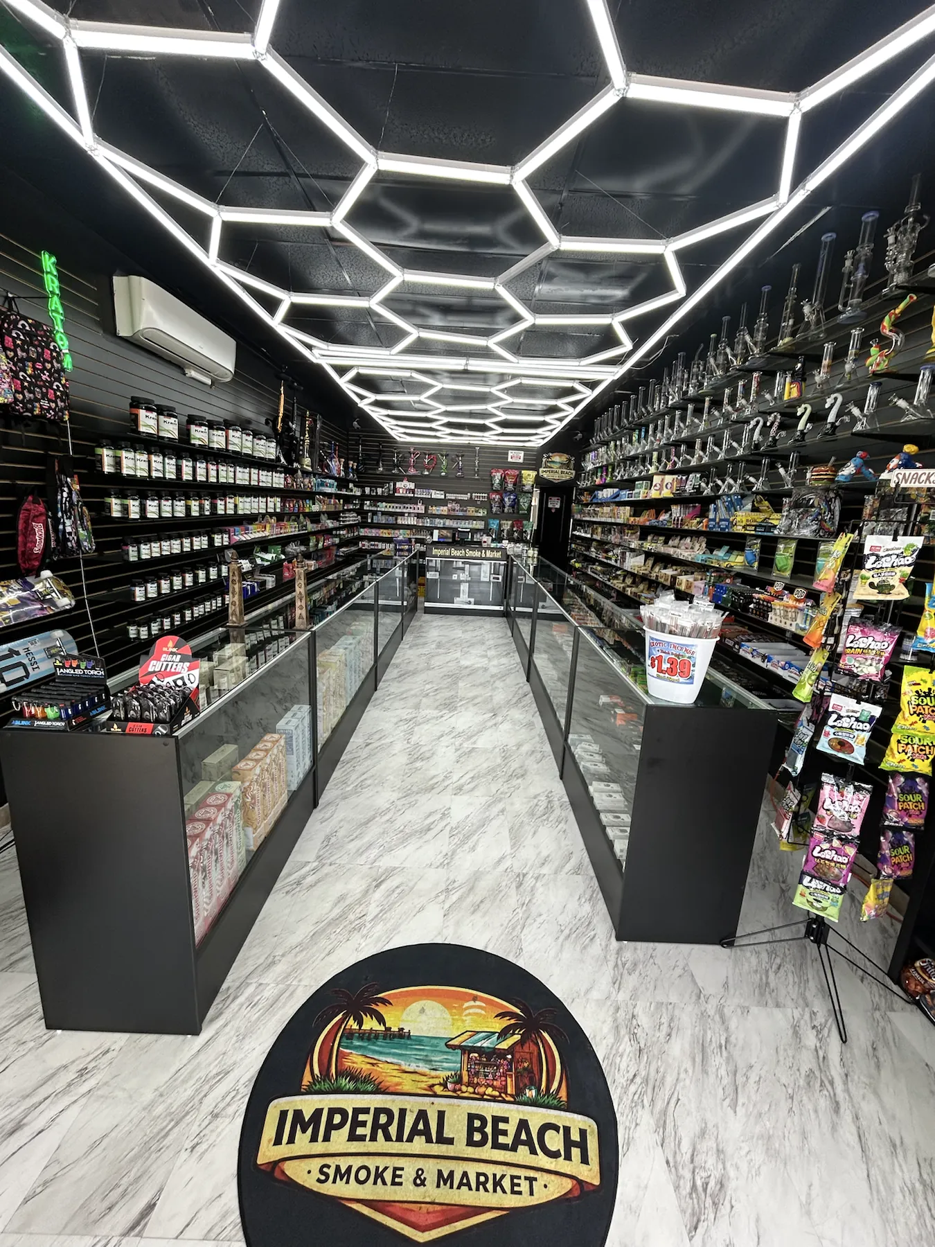 Main aisle and glass display cases inside Imperial Beach Smoke & Market